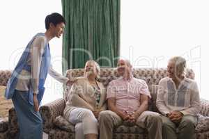 Female doctor interacting with senior people in living room
