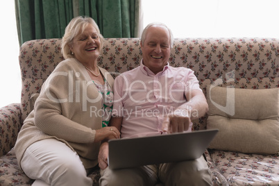 Senior couple using laptop in living room