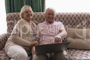 Senior couple using laptop in living room