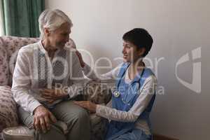 Female doctor interacting with senior woman in living room