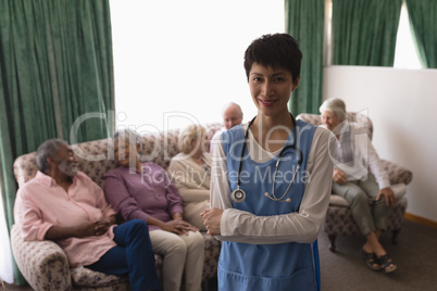 Female doctor standing with arms crossed in living room