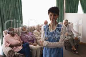 Female doctor standing with arms crossed in living room