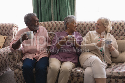 Senior people interacting with each other while having coffee in living room