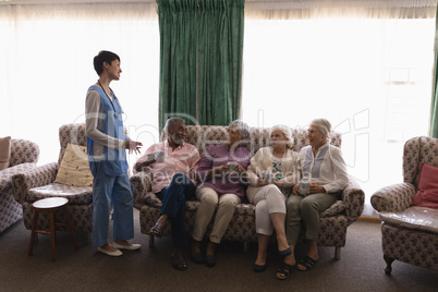 Female doctor interacting with senior people in living room