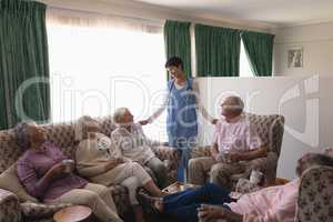 Female doctor interacting with senior people in living room