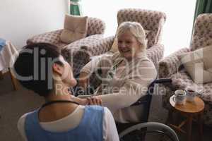 Female doctor interacting with disabled senior woman in living room