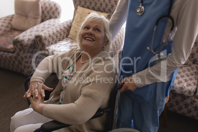 Female doctor interacting with disabled senior woman in living room