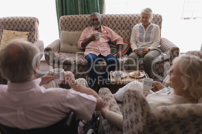 Senior couples interacting with each other while having coffee in living room