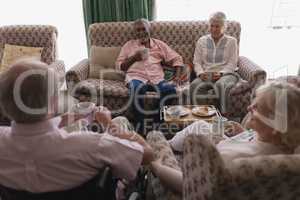 Senior couples interacting with each other while having coffee in living room