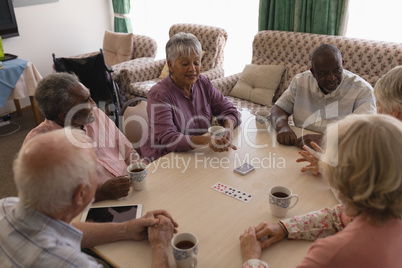 Group of senior people playing cards in living room
