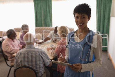 Female doctor holding clipboard and pen in living room