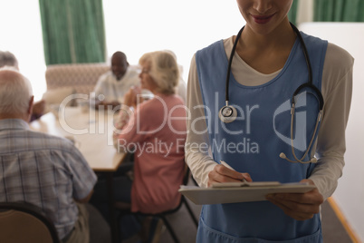 Female doctor holding clipboard and pen in living room at home