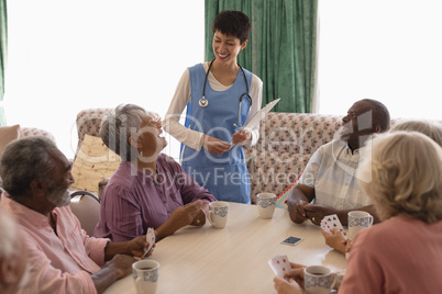 Female doctor interacting with senior people in living room