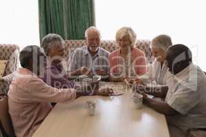 Group of senior people playing cards in living room