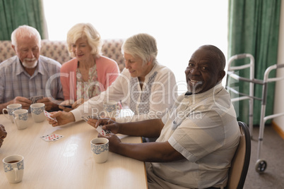 Group of senior people playing cards in living room