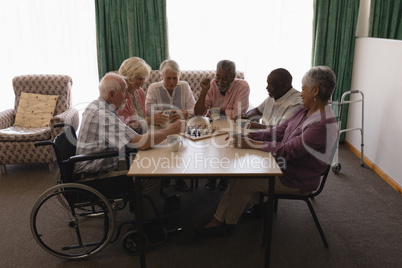 Group of senior people playing chess in living room
