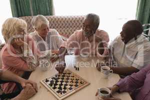 Group of senior people playing chess in living room