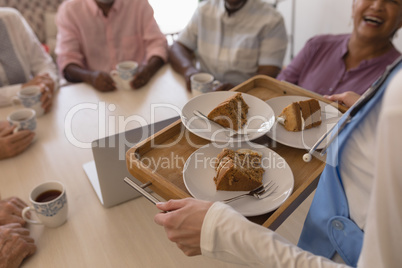 Female doctor holding tray of cake at home