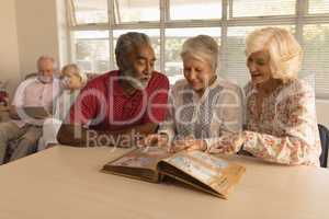 Group of senior people looking at photo album at nursing home