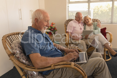 Senior man using laptop while senor couple using digital tablet at nursing home