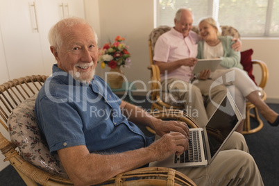 Senior man using laptop while senor couple using digital tablet at nursing home