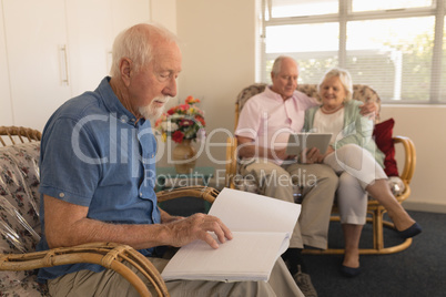 Blind senior man reading a braille book while senior couple using digital tablet at nursing home