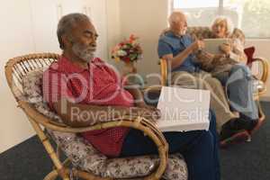 Blind senior man reading a braille book while senior couple using digital tablet at nursing home