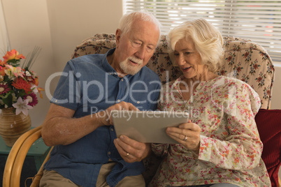 Senior couple using digital tablet in living room