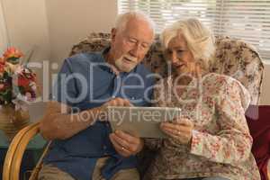 Senior couple using digital tablet in living room