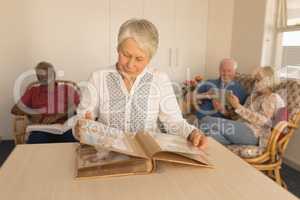 Senior woman looking at photo album in living room