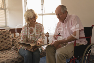 Senior couple looking at photo album in living room