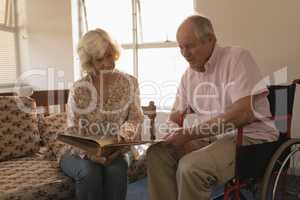 Senior couple looking at photo album in living room