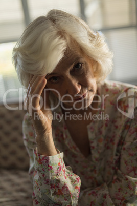 Worried senior woman relaxing on sofa in living room