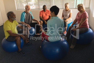 Female trainer training senior people in performing exercise