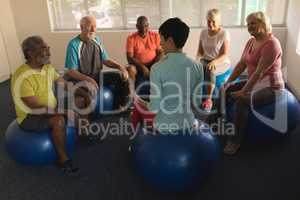 Female trainer training senior people in performing exercise