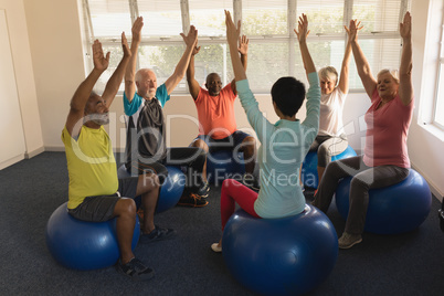 Female trainer training senior people in performing exercise