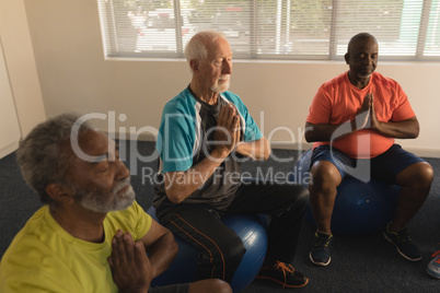 Group of senior men performing yoga at home