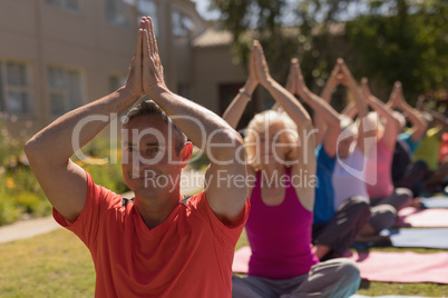 Trainer training senior people in performing yoga