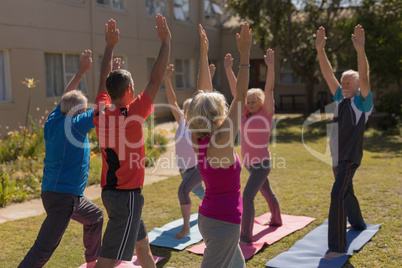 Trainer training senior people in performing exercise