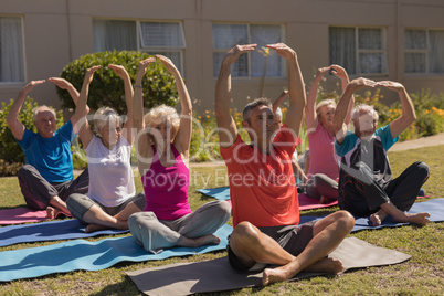 Trainer training senior people in performing exercise