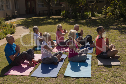 Trainer training senior people in performing yoga