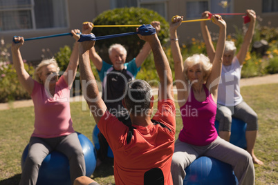 Trainer training senior people in performing exercise