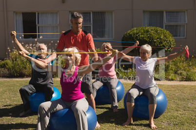 Trainer assisting senior women in performing exercise