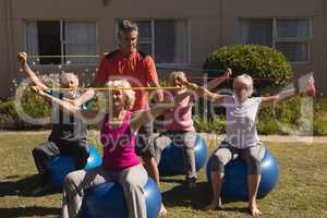 Trainer assisting senior women in performing exercise