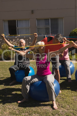 Trainer assisting senior women in performing exercise