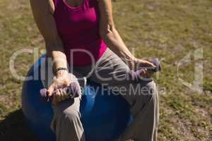 Senior woman exercising with dumbbells in the park