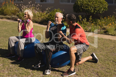 Trainer assisting senior man in performing exercise