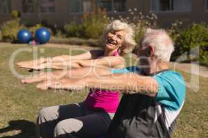 Senior man and senior woman performing stretching exercise in the park