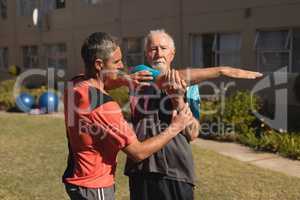 Trainer assisting senior man in performing exercise