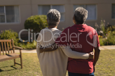 Senior couple standing with arm around in the park